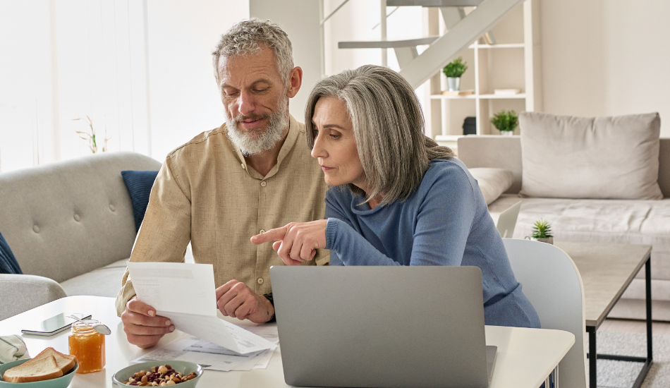 Senior mature couple check bank loan documents using laptop at home.